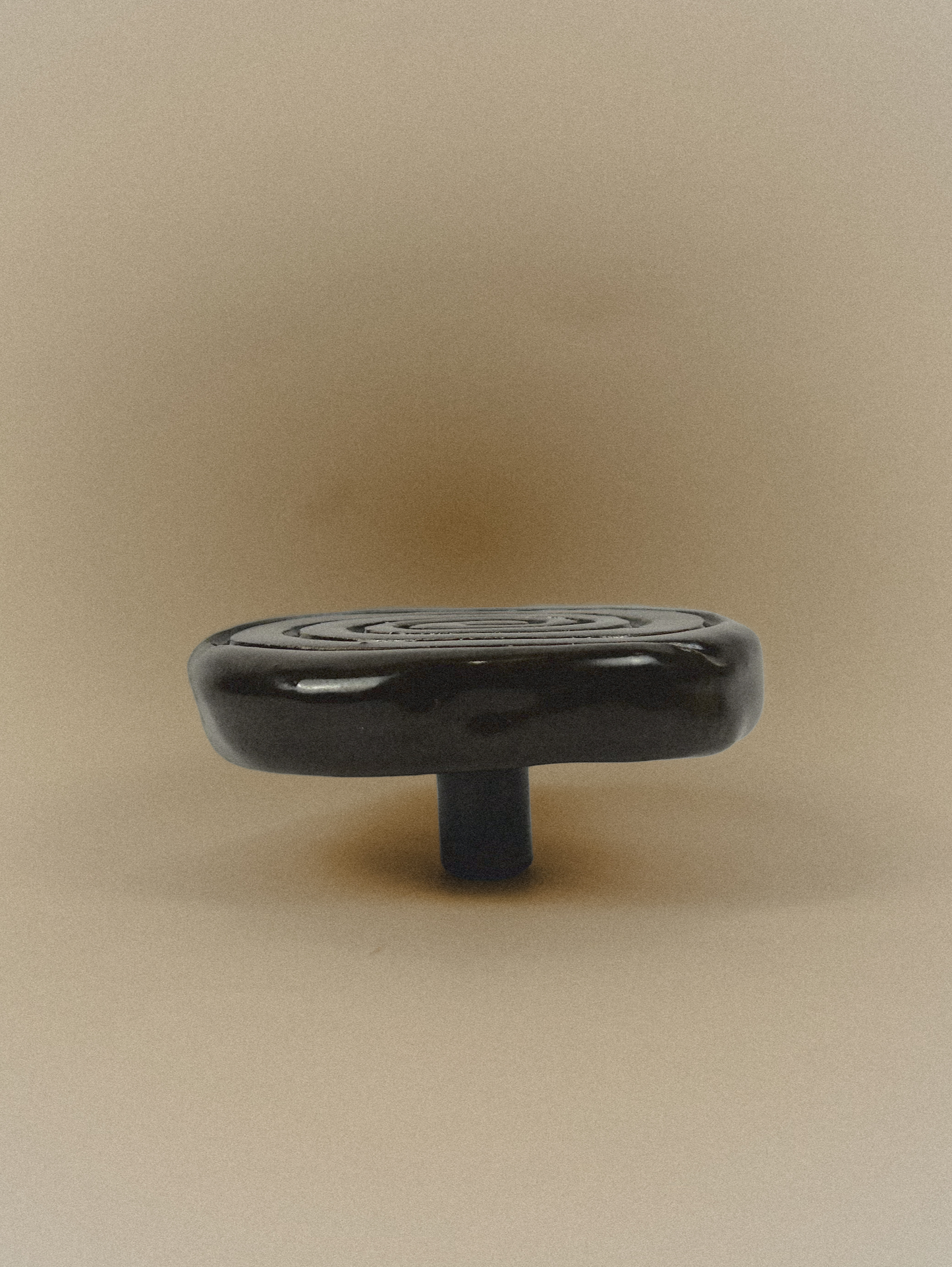 Black cabinet knob on a beige background