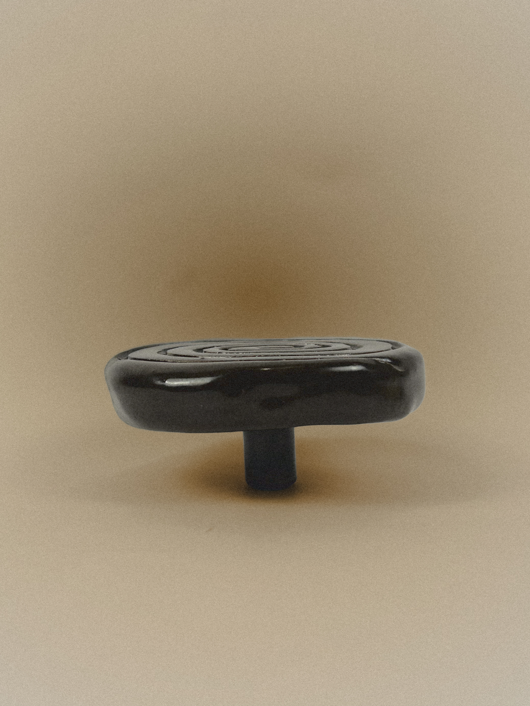 Black cabinet knob on a beige background